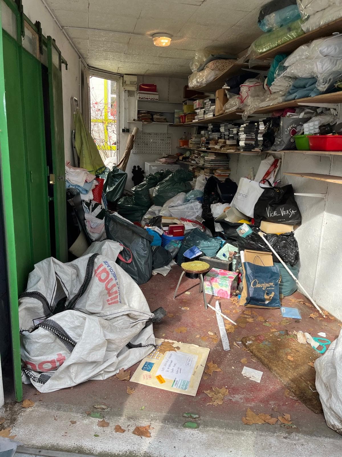Garage encombré de sacs, vêtements et étagères pleines avant vidage