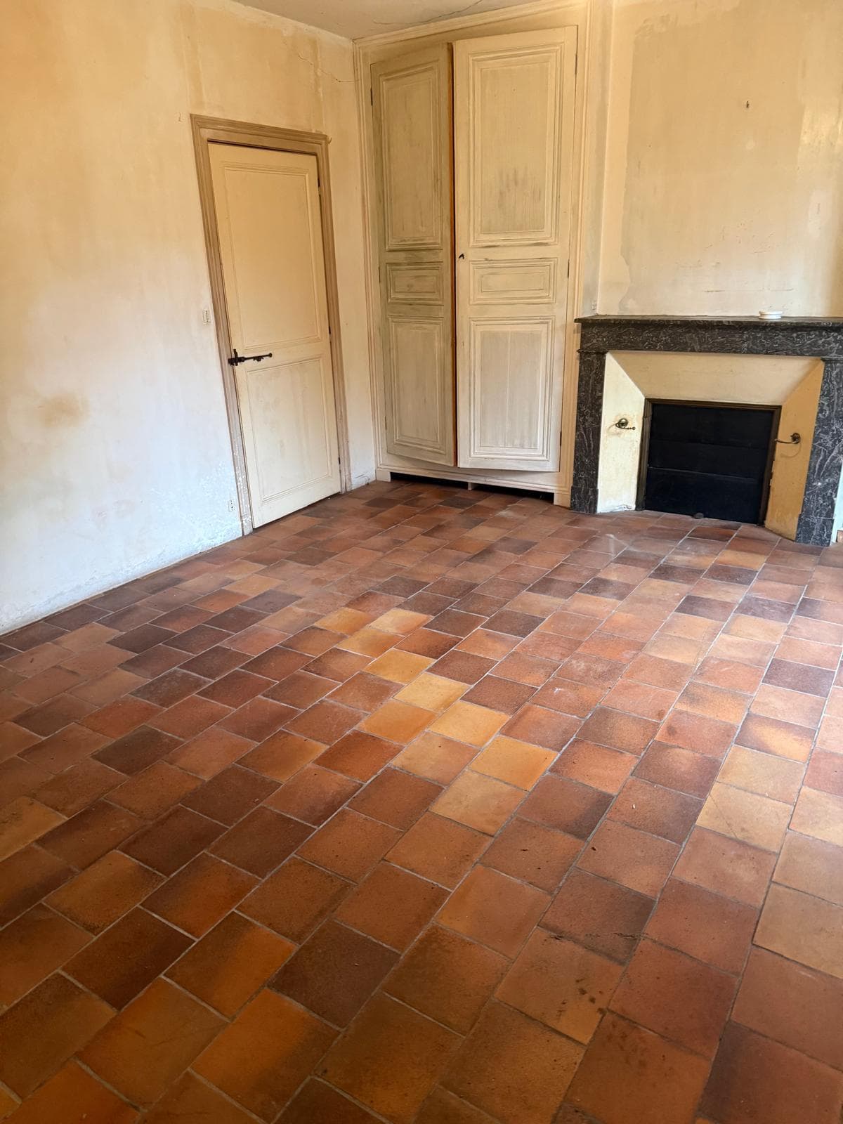 Pièce de maison de campagne vidée avec grande cheminée en pierre après débarras