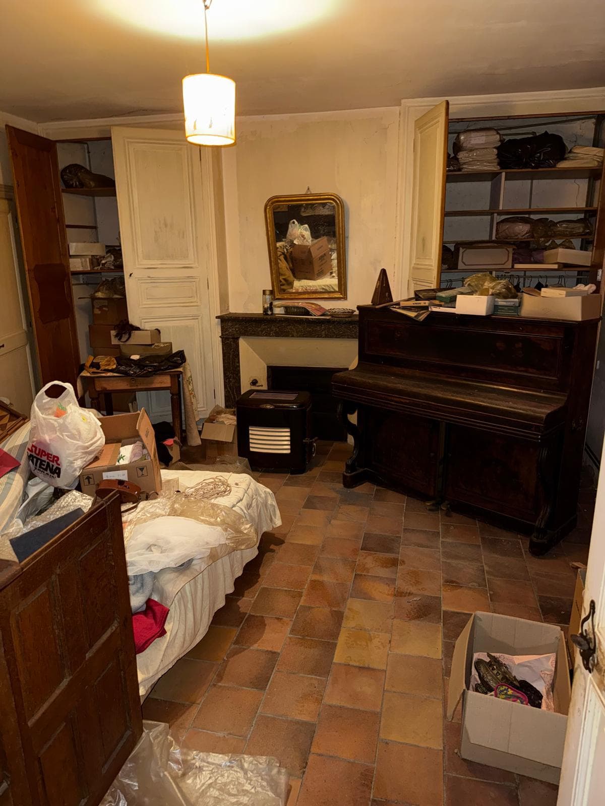 Pièce encombrée avec piano, armoire et cartons avant débarras de maison