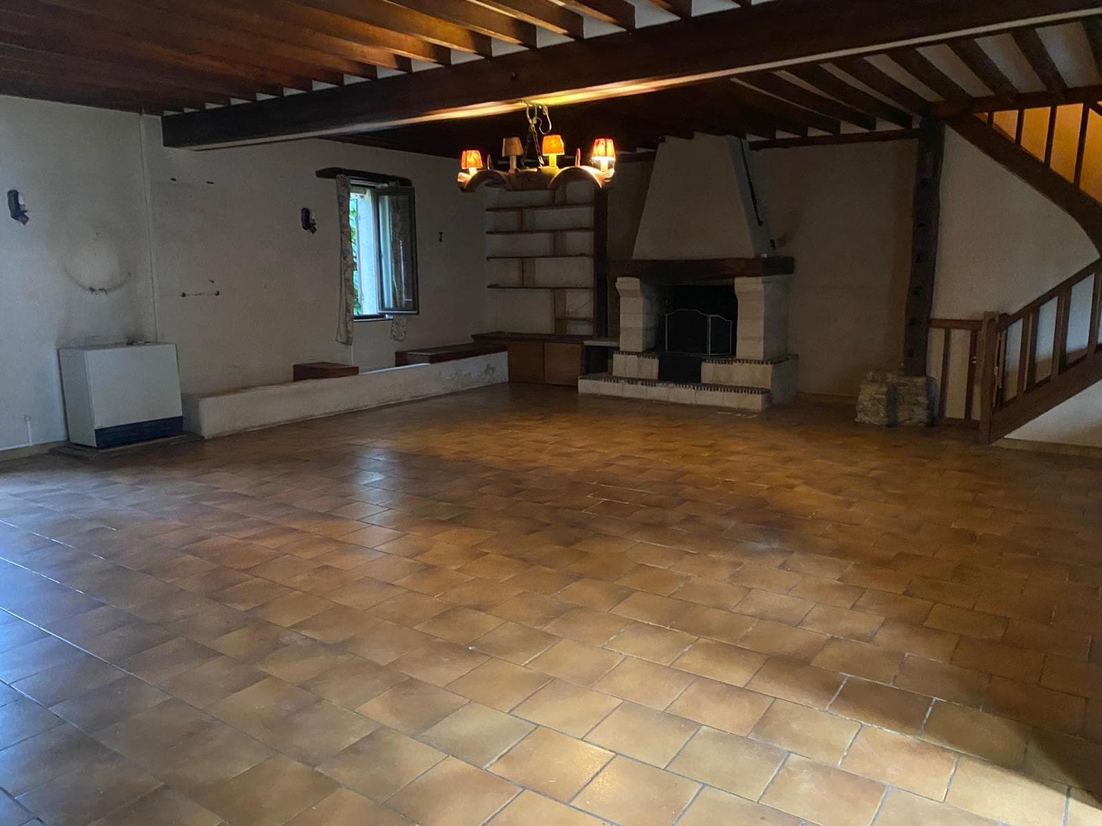 Séjour entièrement vidé avec cheminée et tomettes visibles après débarras